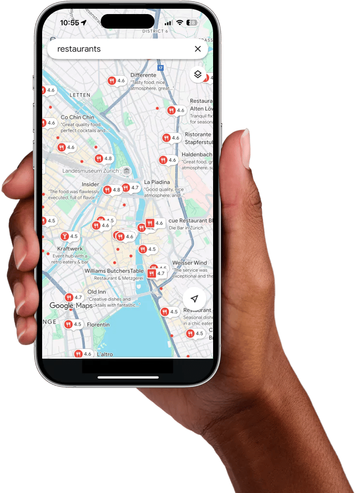A hand holding a mobile phone with Google Maps opened searching for restaurants in Zurich